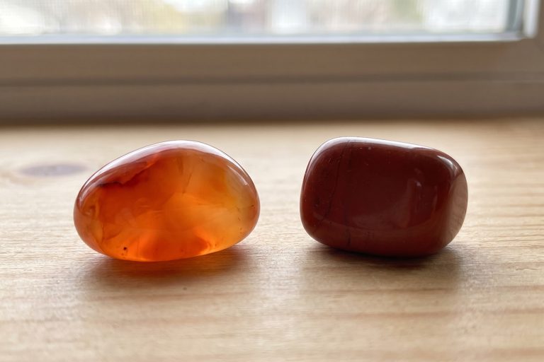 A translucent orange-red carnelian tumble and an opaque brick-red jasper pebble