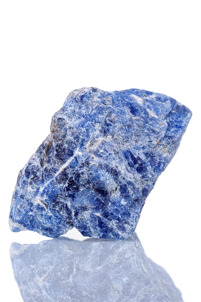 Raw sodalite specimen with rough blue surface, white calcite veining, and natural angular crystalline texture.
