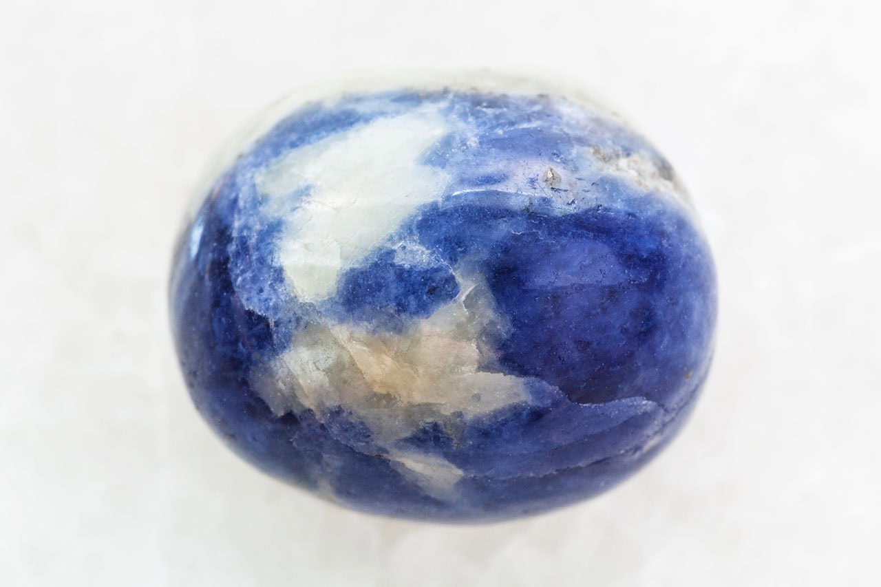 Polished sodalite stone with smooth glossy finish, deep blue color and flowing white veins throughout.