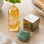Healing crystals including citrine, pyrite, and aventurine on a wooden surface.