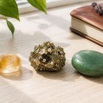 Collection of healing crystals including citrine, pyrite, and green aventurine on a wooden surface.