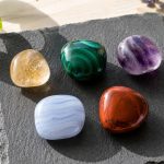 Colorful healing crystals on black slate for wellness and energy.
