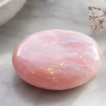 Polished pink rose quartz crystal on marble surface for healing and meditation.