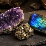 Amethyst cluster, raw pyrite, and flashing labradorite on a dark slate tile.